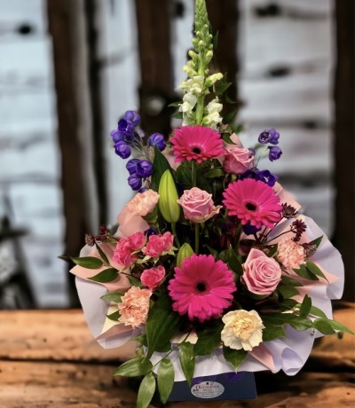 Vibrant Frontal - It contains roses, gerberas, lilies, carnations, lush greenery and other filler seasonal flowers. its delivered in a box and can be left as it is for the duration and waterd daily, take a look at our other products with the same design but with various colours. 