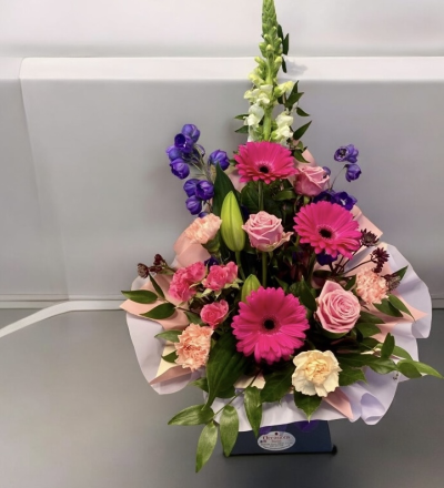 Vibrant Frontal - It contains roses, gerberas, lilies, carnations, lush greenery and other filler seasonal flowers. its delivered in a box and can be left as it is for the duration and waterd daily, take a look at our other products with the same design but with various colours.